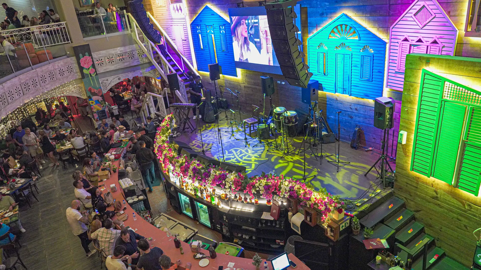 Vista del salón de JALAO con la tarima de música en vivo y casitas de colores